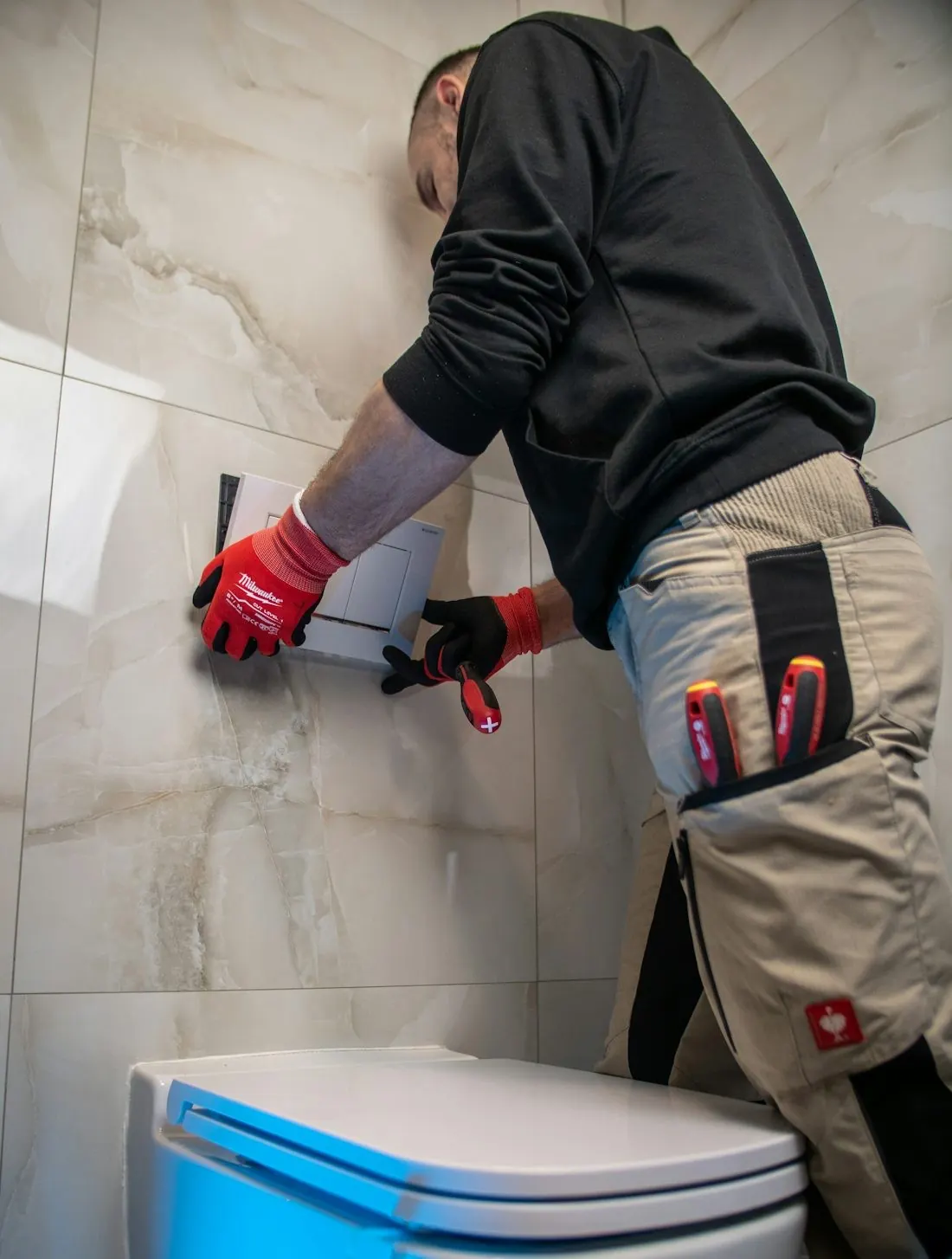 Un ouvrier pose de la céramique près d'une toilette.