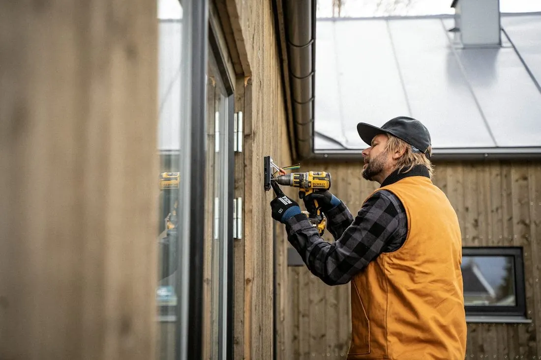 Un ouvrier perce un mur extérieur en hiver.
