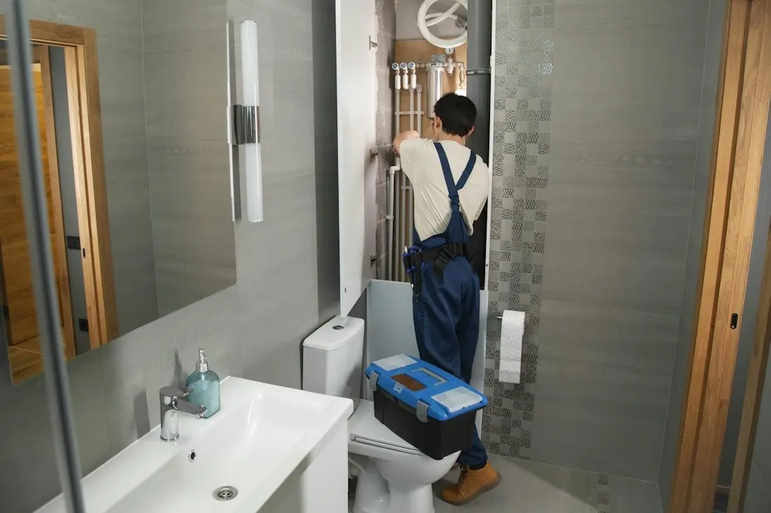 Un plombier au travail dans une salle de bain en rénovation.